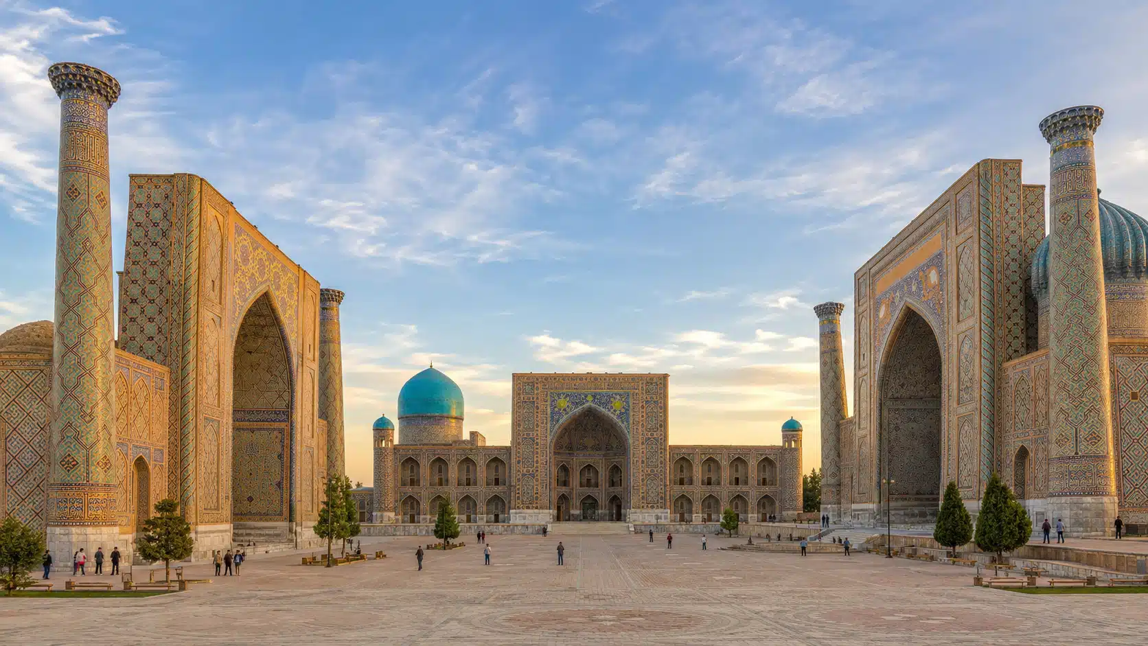 Illustration de la place du Registan à Samarcande, avec ses trois madrasas aux façades de céramique turquoise, sous un ciel dégagé de fin d'après-midi printanière.
