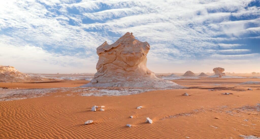 Formation rocheuse spectaculaire dans le désert blanc d'Égypte, sous un ciel bleu parsemé de nuages