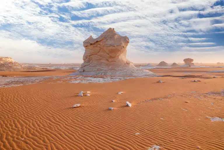 Formation rocheuse spectaculaire dans le désert blanc d'Égypte, sous un ciel bleu parsemé de nuages